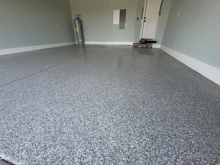 Another angle of finished epoxy floor coating — garage with white trim and gray speckled flake floor