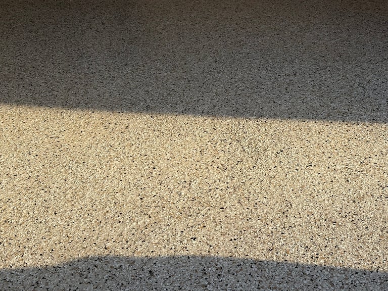 Overhead view of asphalt road with center gravel or concrete stripe in bright sunlight showing exposed aggregate texture