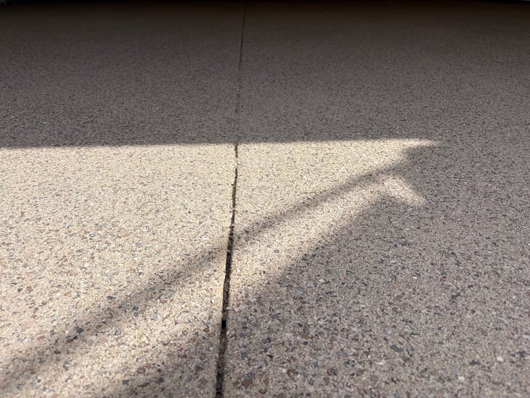 Shadow of a railing cast on a concrete floor with light and dark sections showing clean vs worn concrete