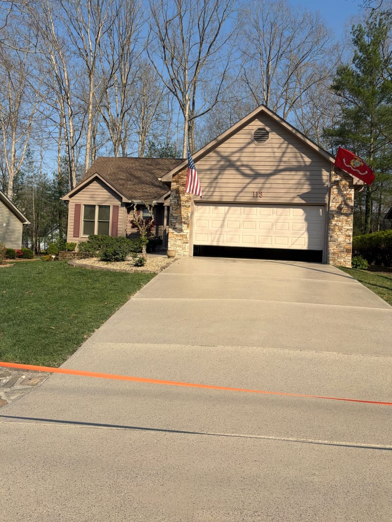 Single-story beige house with brick accents, two-car garage, and American flag on mailbox