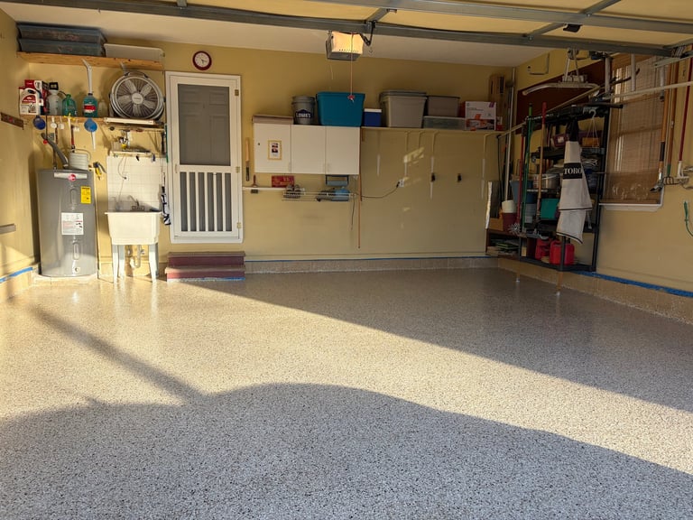 Finished epoxy floor coating installation — spacious garage interior with beige walls and speckled decorative flake floor