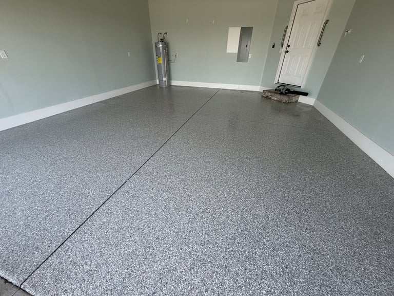 Empty garage interior with gray speckled epoxy floor, white walls, and closed doors