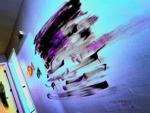 Large wall mural of purple, gray, and black brushstrokes over a teal-blue wall, with small painted fish artwork at the bottom left