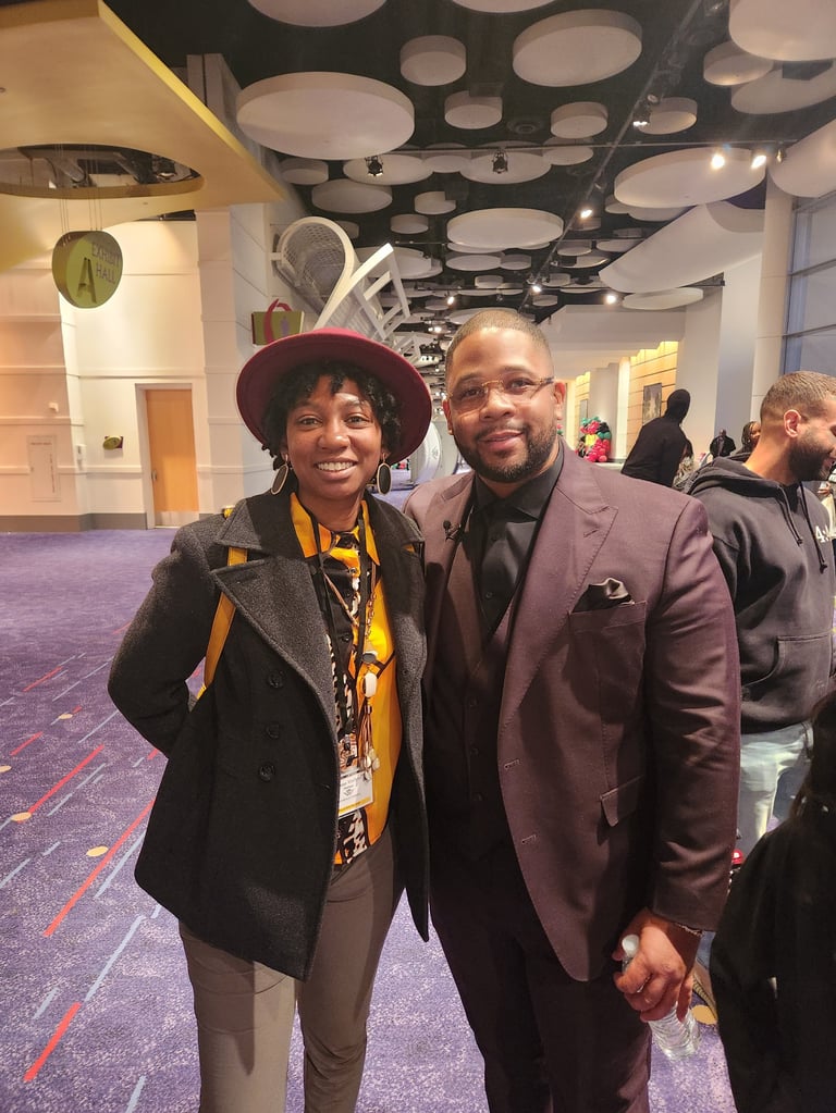 Two people smiling at camera in modern venue with purple carpet and geometric ceiling design