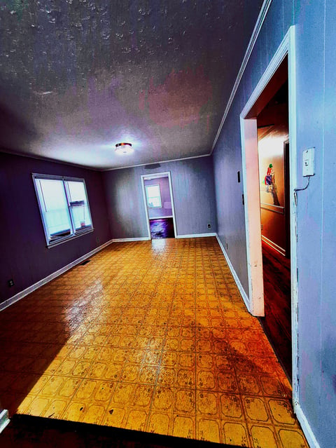 Empty interior room with yellow patterned floor, purple walls, ceiling light, windows, and open doorway to another room