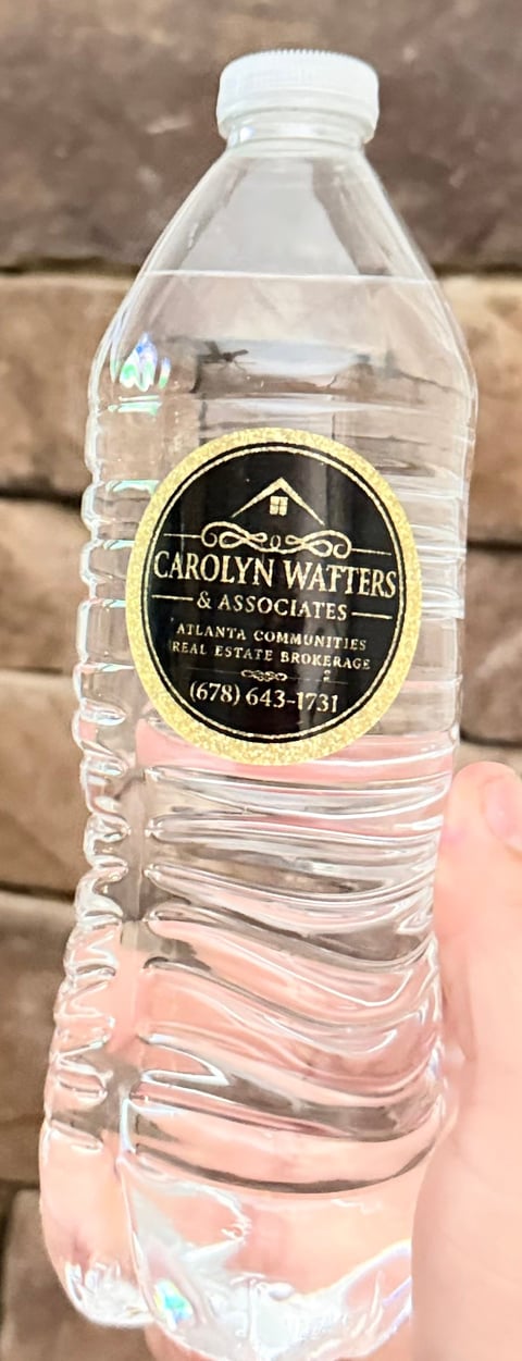 Clear plastic water bottle with gold and black Carolyn Watters & Associates custom label