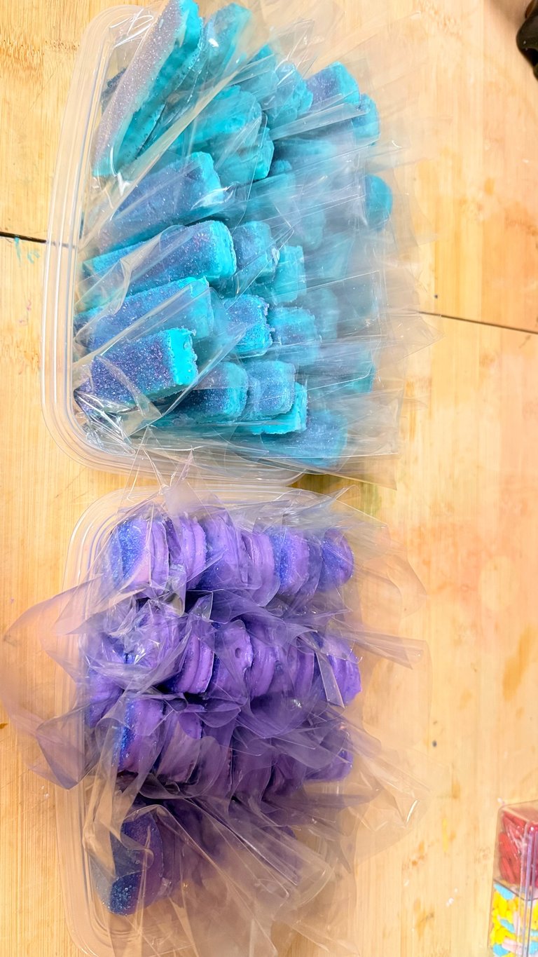 Two clear plastic containers of decorative tulle bows on wood surface - turquoise and purple colors