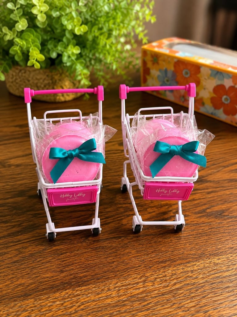 Two miniature toy shopping carts with pink cushions, teal bows, and pink handles on a wooden surface