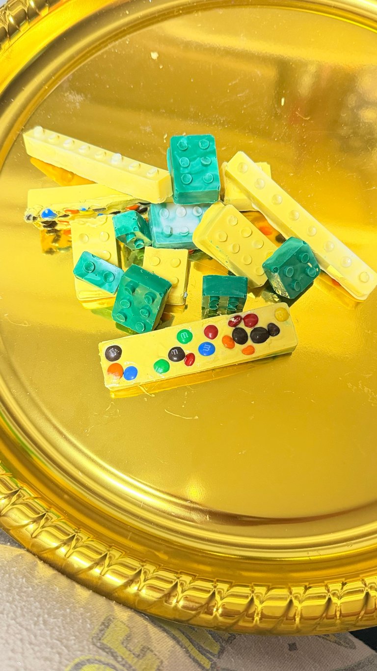Colorful building blocks and paint palette arranged in a yellow container, featuring green and yellow LEGO-style bricks with scattered colorful paint dots