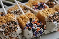 Four triangular dessert slices with caramel drizzle, granola topping, and blue flower garnish on white plates