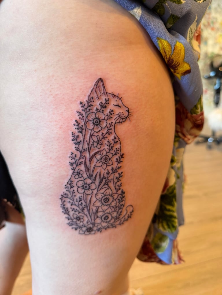 Tattoo of a rabbit silhouette filled with detailed floral and botanical line art on upper thigh