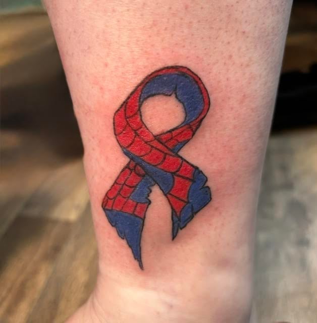 Red and blue ribbon tattoo on leg in a figure-eight or infinity symbol shape on fair skin