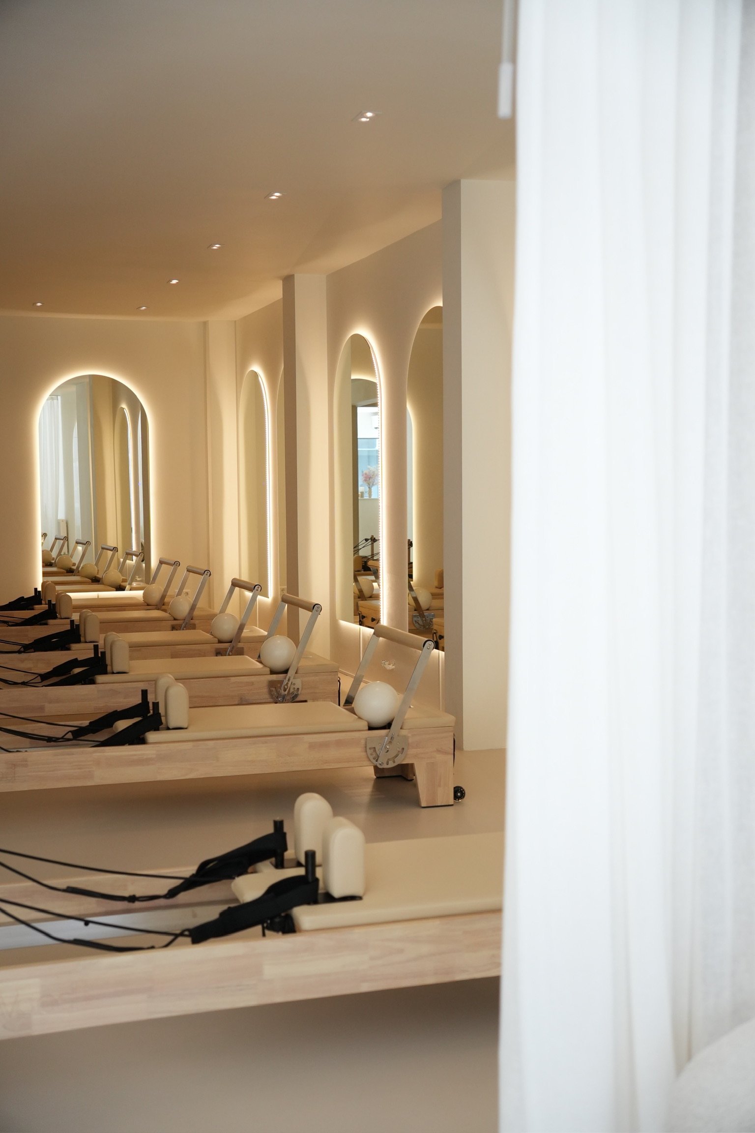 Modern hair salon with row of vanity mirrors with warm LED lighting and wooden countertop with black cords