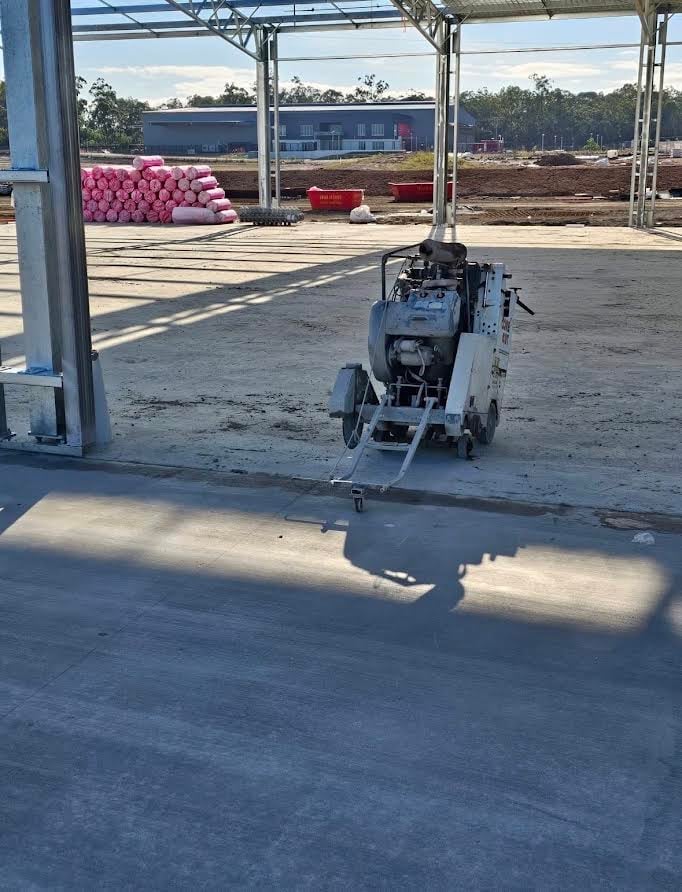 Concrete cutting machine on warehouse floor with construction materials