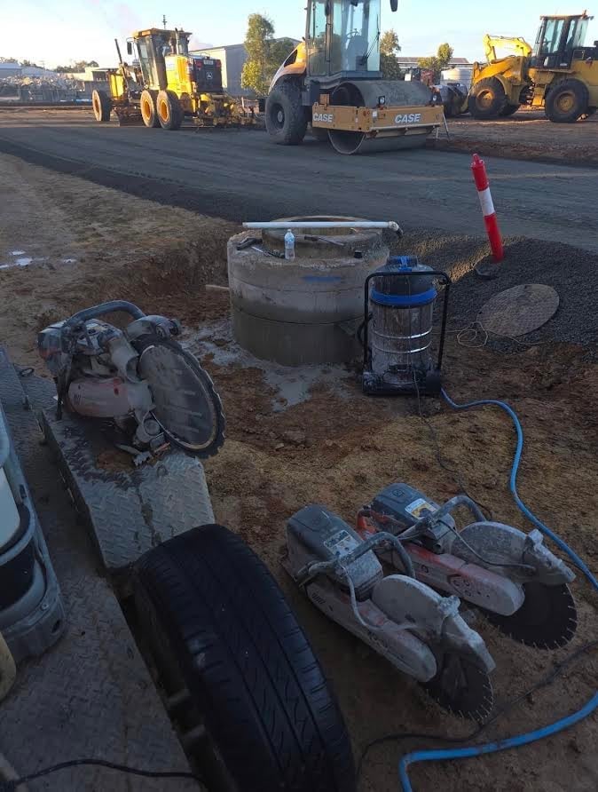 Road construction site with heavy machinery and workers preparing asphalt