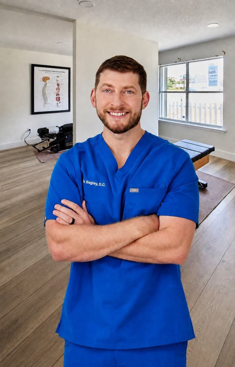 Dr. Taylor Bagley, D.C. — pediatric and family chiropractor in Navarre FL, standing in scrubs inside the Bagley Chiropractic clinic