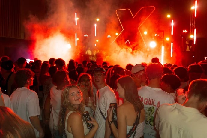 Crowded concert or music festival at night with red and orange neon stage lighting and fog effects