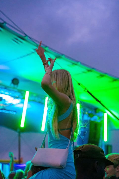 Woman with blonde hair dancing at a nightclub with neon green and blue lighting