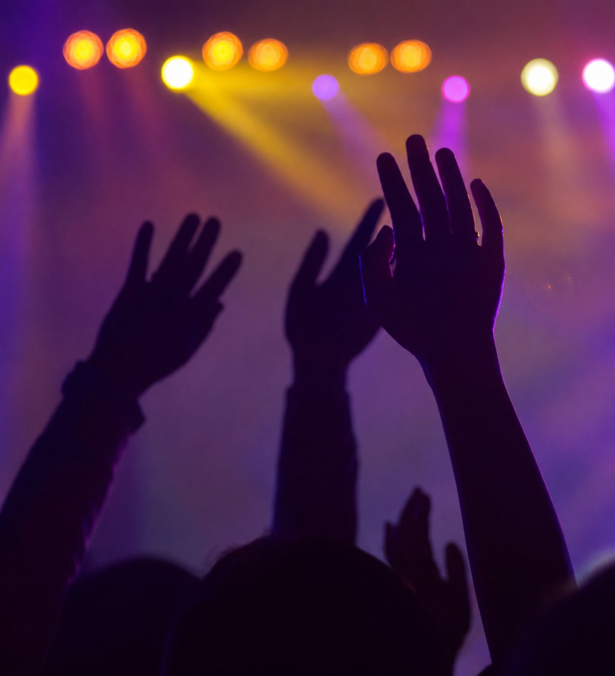 Concert stage lighting with moving heads and colourful beams sweeping over crowd