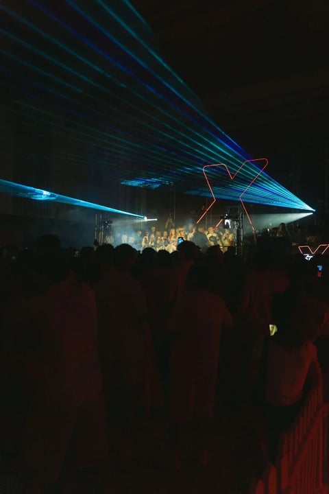 Concert stage with dramatic blue and red laser light show beaming across the audience at night