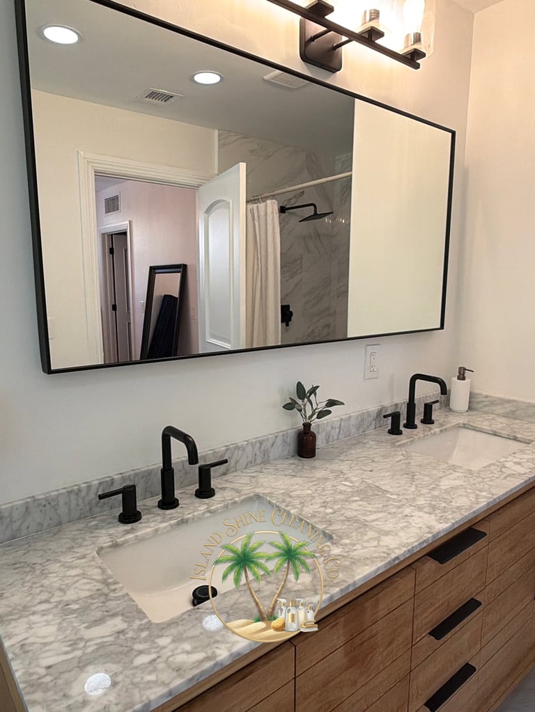 Modern bathroom vanity with marble countertop, dual sinks with black faucets, and large black-framed mirror above