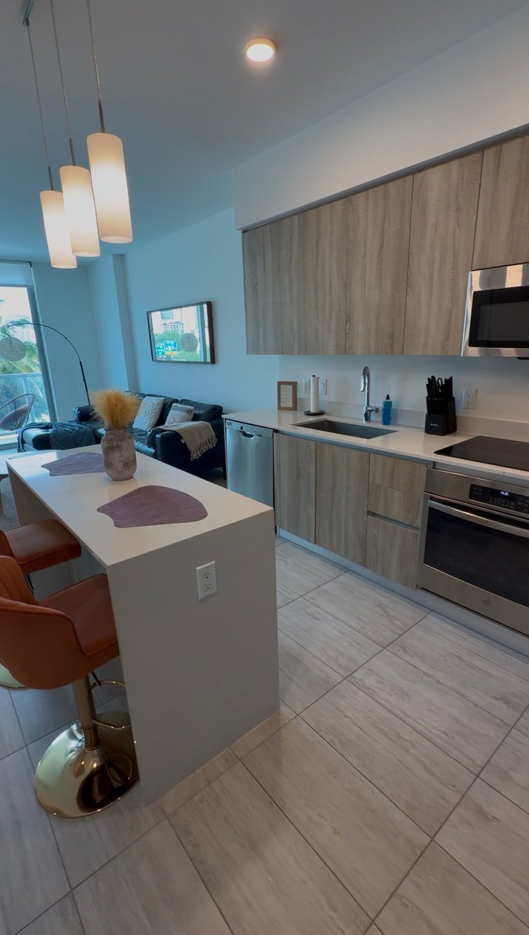 Modern kitchen interior with white island, wood cabinetry, stainless steel appliances, pendant lights, and blue accent wall