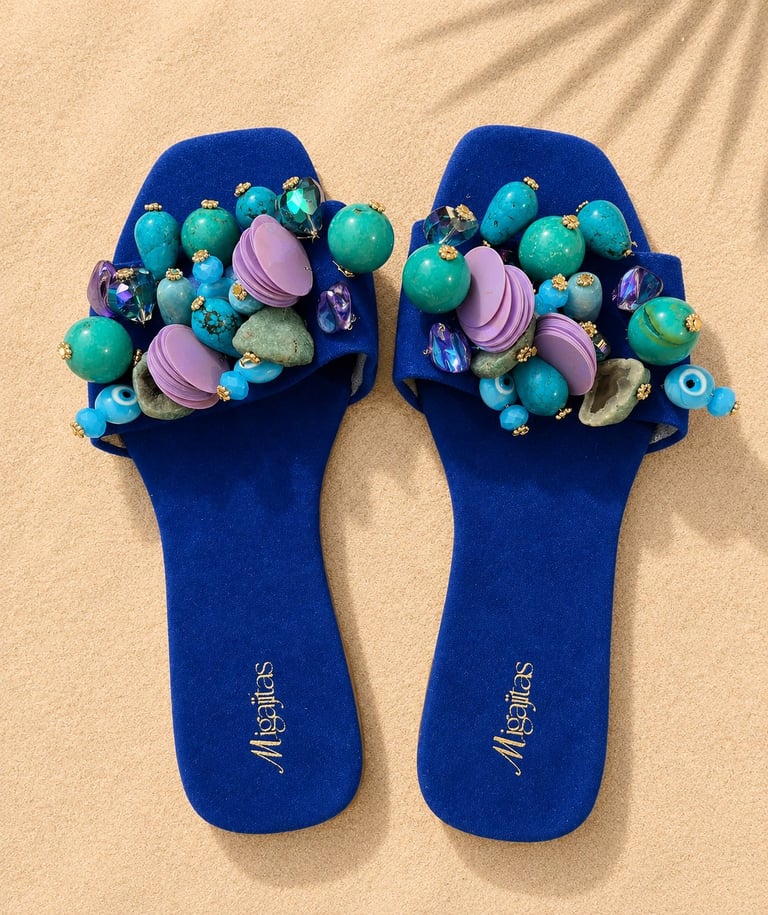 Pair of blue slides with colorful beaded embellishments including green, turquoise, pink, and purple decorative beads on the straps