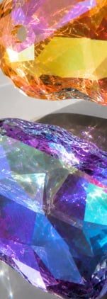 Colorful translucent gemstones displaying orange, yellow, purple, blue and cyan hues with light reflections