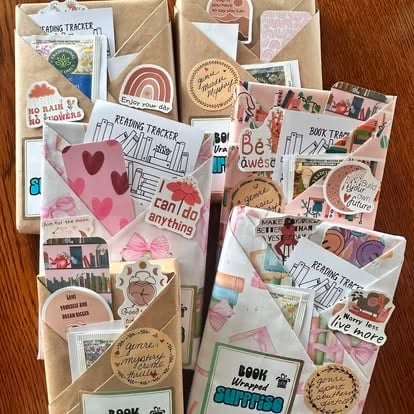 Flat lay collection of DIY scrapbooking stickers, washi tape, stamps, and reading tracker decorations on wood surface
