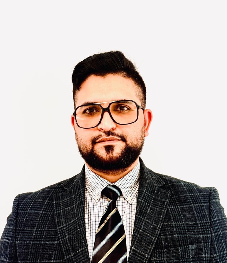 Ghulam Ali Hassan, Legal Caseworker at Legalise It Solicitors, professional headshot wearing a dark plaid blazer, checkered shirt and striped tie against a white background