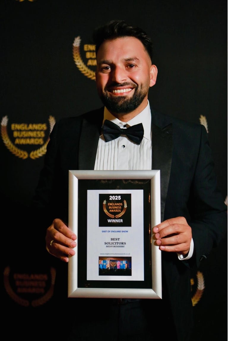 Man in formal tuxedo holding England Business Awards 2025 winner plaque against dark background with gold award logos
