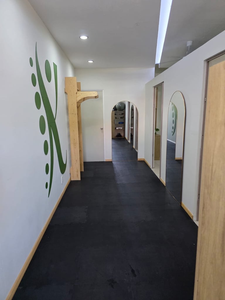 Pasillo de la clínica con isotipo verde en la pared, espejos y puertas de madera clara