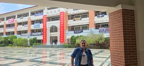 Person standing in courtyard of modern building with brick facade and red vertical banners