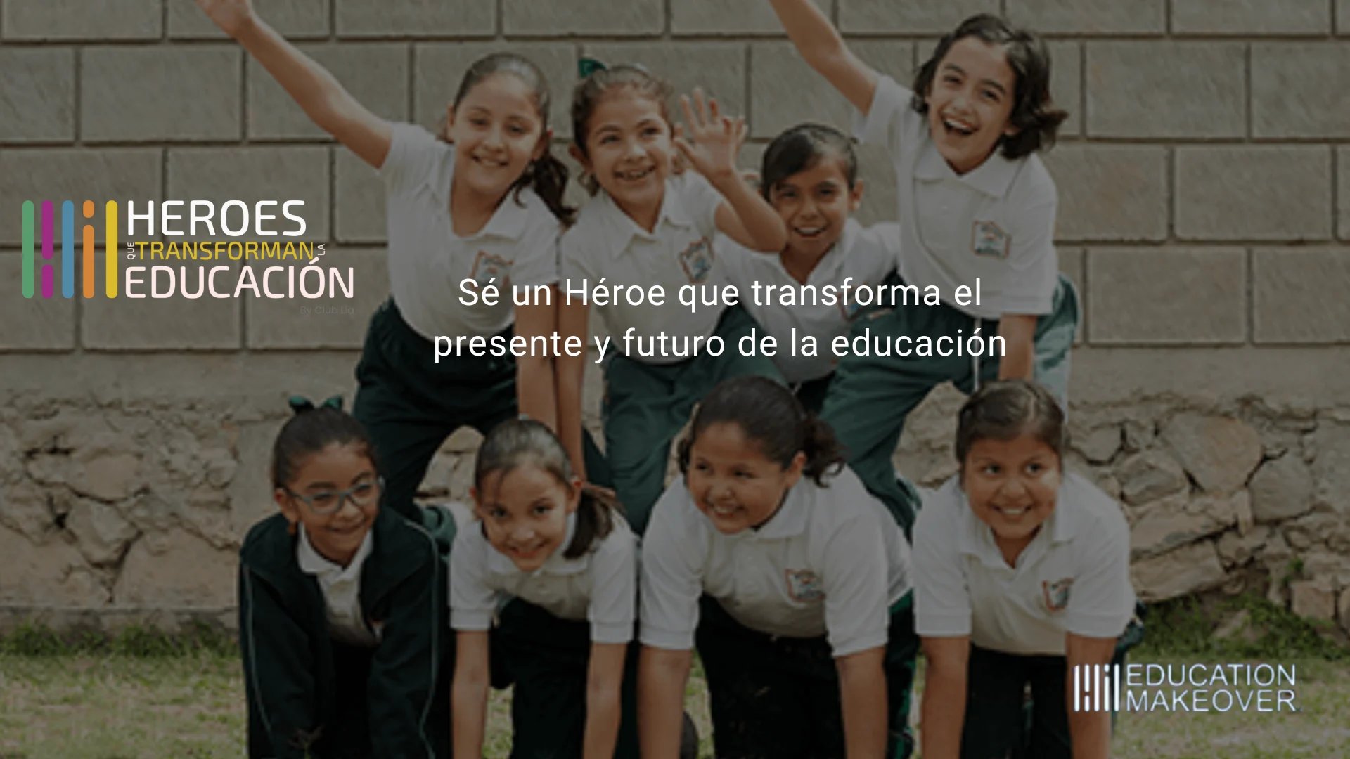Group of smiling schoolchildren in uniforms posing against a brick wall with education program logos and Spanish text