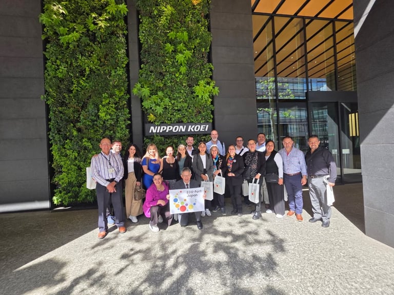 Group of people posing for photo at Nippon Koei office entrance with green wall and modern architecture