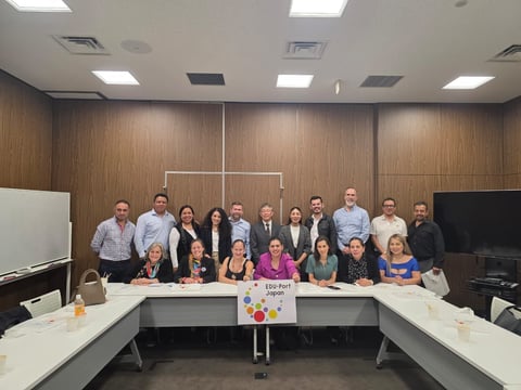 Group photo of approximately 20 diverse professionals in business casual attire posed in a conference room around a U-shaped table