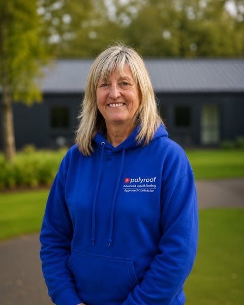 Woman smiling at camera wearing blue Polyroof branded hoodie, standing outdoors with house and trees in background