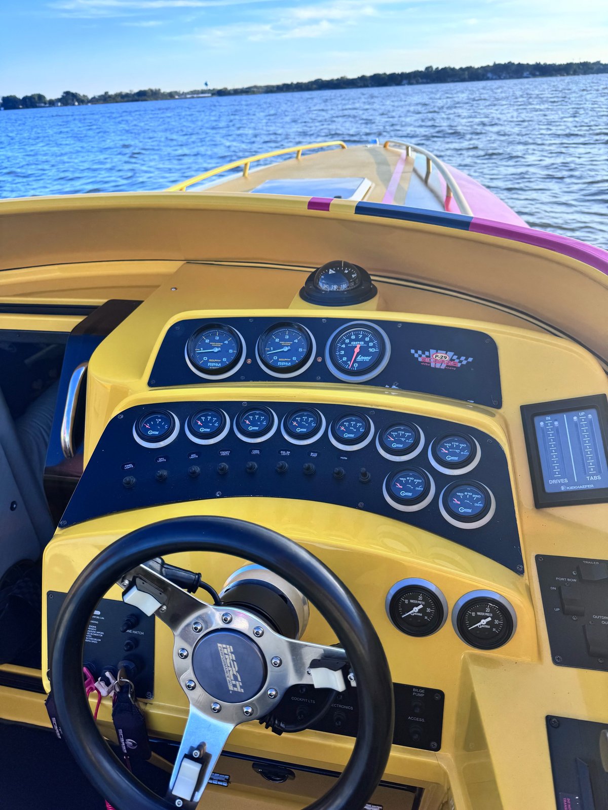 View from the helm of the P-29 looking over the yellow dash, Livorsi gauges and Kiekhaefer drive and tab indicators out across the bow at open water