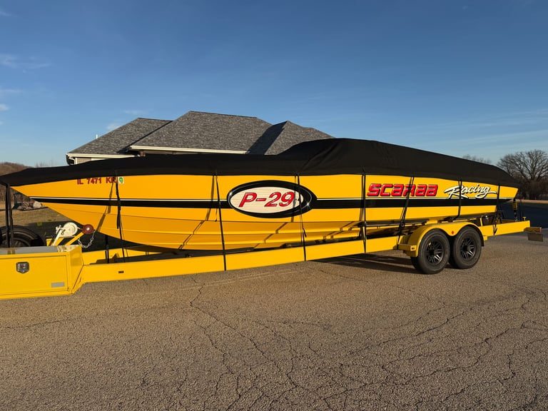 Yellow and black enclosed boat trailer with Scarab P-29 Scuba branding parked in a lot