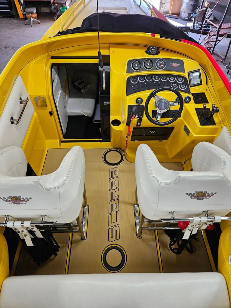 Overhead view of a yellow speedboat interior with white seating, black dashboard, and steering wheel docked in a warehouse