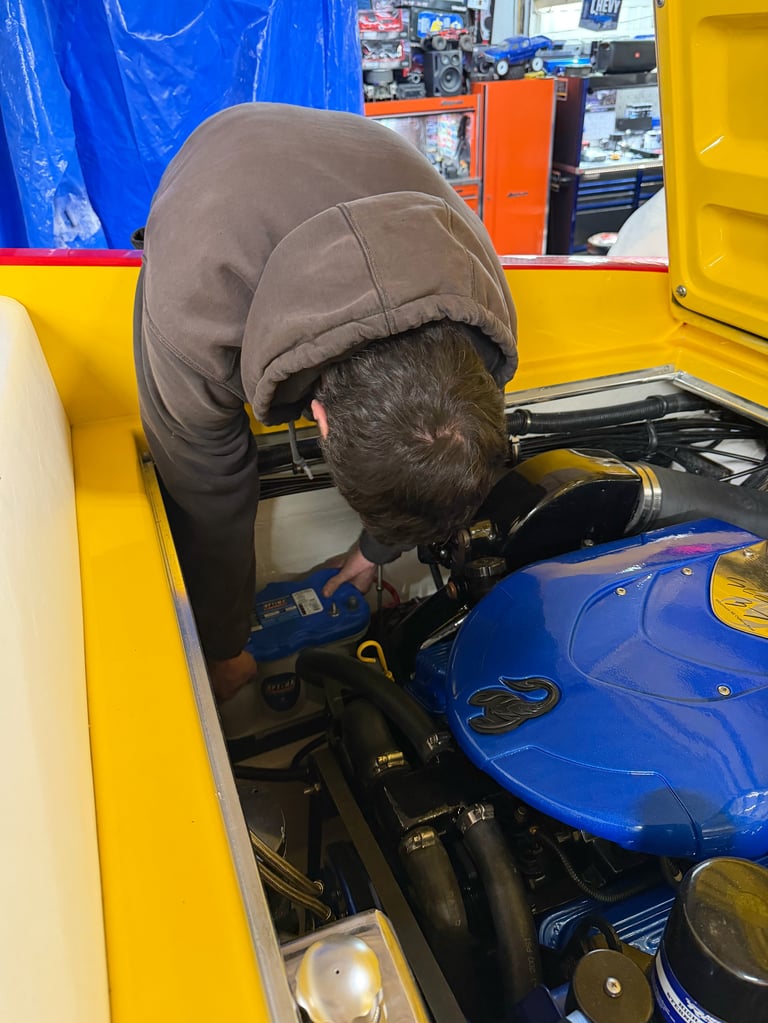 Working on the blue motorcycle in the garage, framed by the yellow and blue walls