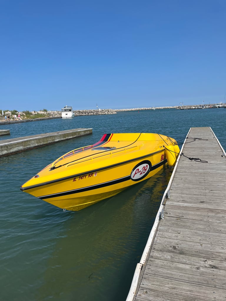 Yellow Scarab P-29 docked at a wooden pier on calm turquoise water with harbor buildings visible across the bay