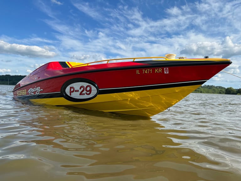 Red and yellow speedboat with P-29 marking on water under blue sky with clouds