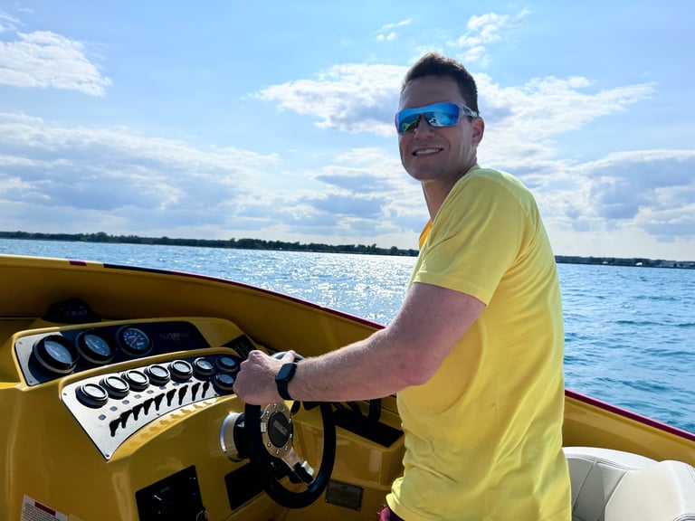 Man in yellow shirt and sunglasses at helm of yellow speedboat on blue water