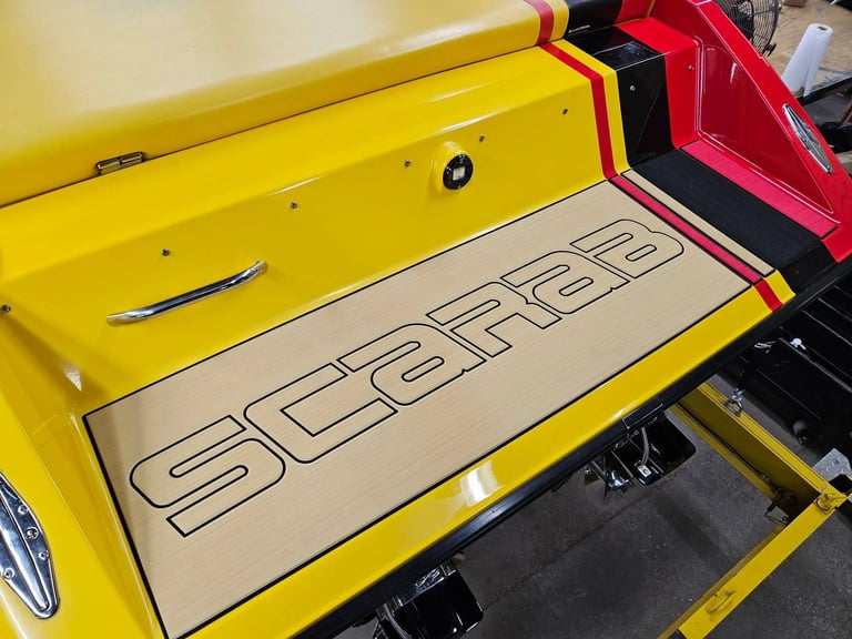 Rear swim platform of the P-29 with custom SeaDek inlay bearing the large SCARAB wordmark in black, set against the yellow hull and red accent stripes