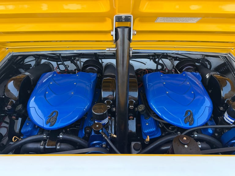 Twin blue V8 engines in a yellow performance car engine bay
