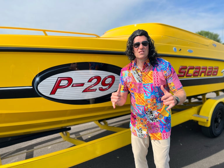 Man in colorful shirt and sunglasses posing in front of yellow speedboat labeled P-29