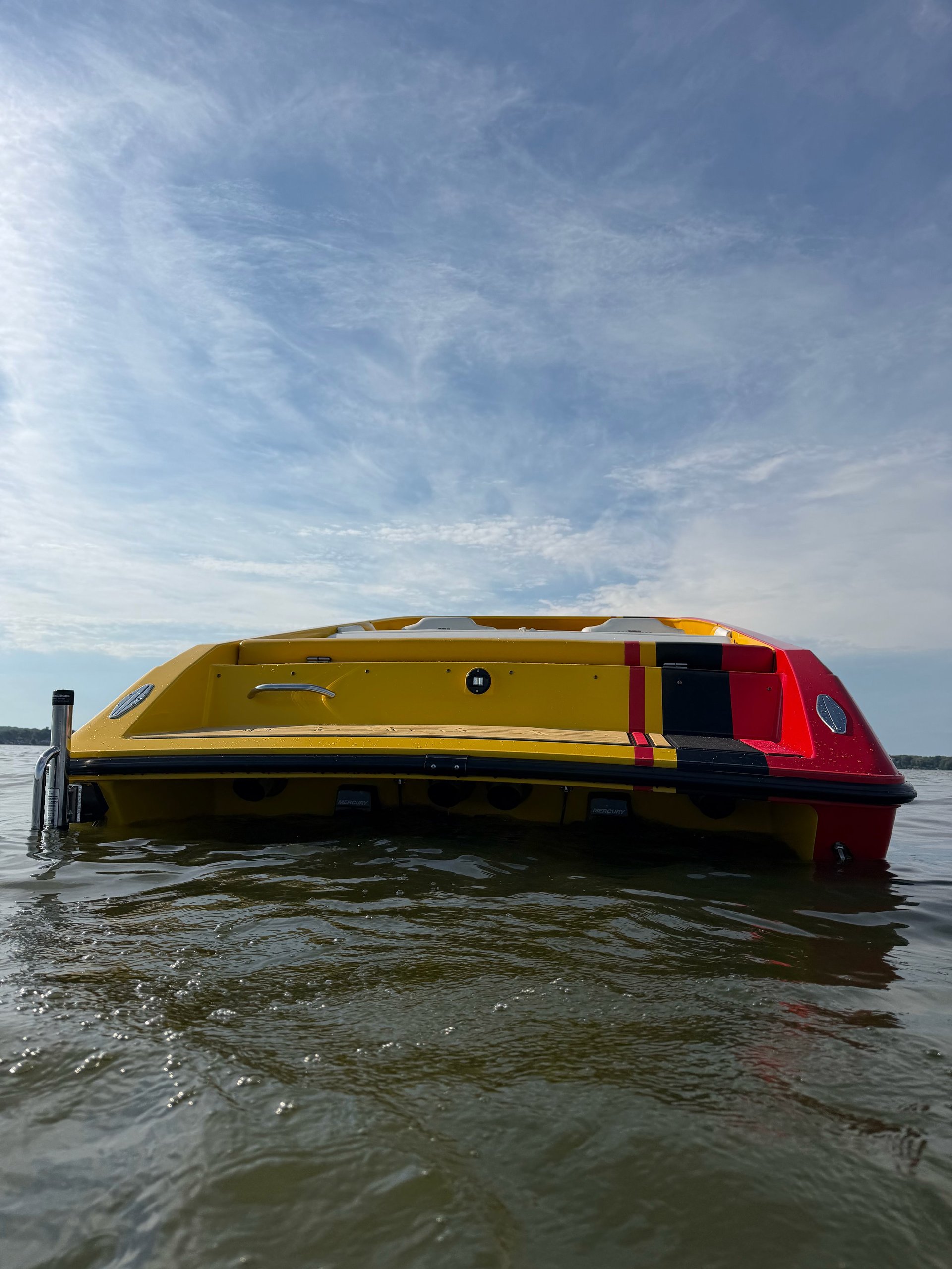 Yellow and red speedboat moored in shallow water on a cloudy day