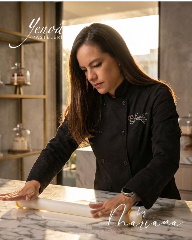Woman in black chefs coat working with dough at marble counter in elegant pastry kitchen