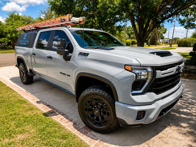 White Chevrolet Silverado pickup truck with roof rack parked on grass, featuring black wheels and outdoor summer setting